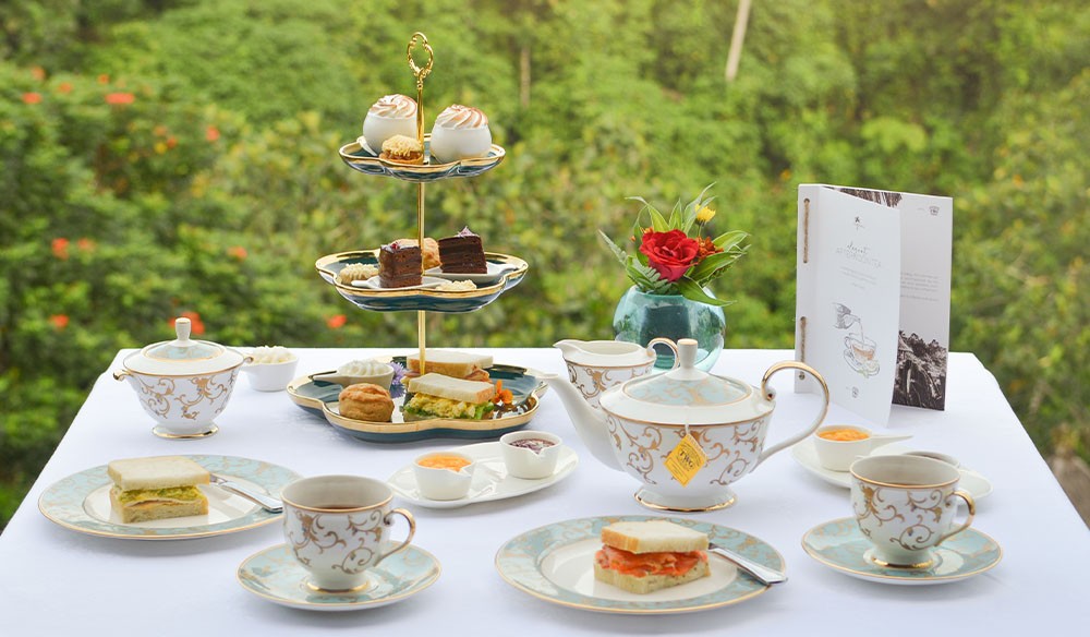 Elegant CasCades Restaurant Afternoon Tea service, featuring a tiered stand of scones, sandwiches, and pastries, alongside fine porcelain teacups and a teapot.