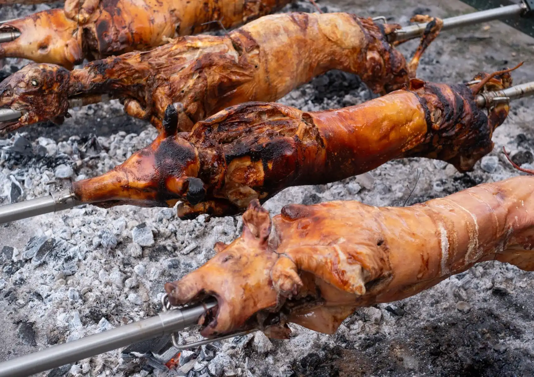 Traditional roast pork on spits over charcoal fire, showcasing authentic Balinese cooking style.