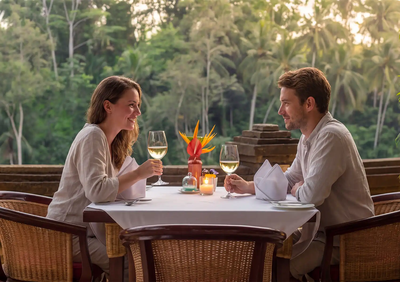 Intimate outdoor restaurant in Ubud with candlelit table, tropical flowers, and forest backdrop.