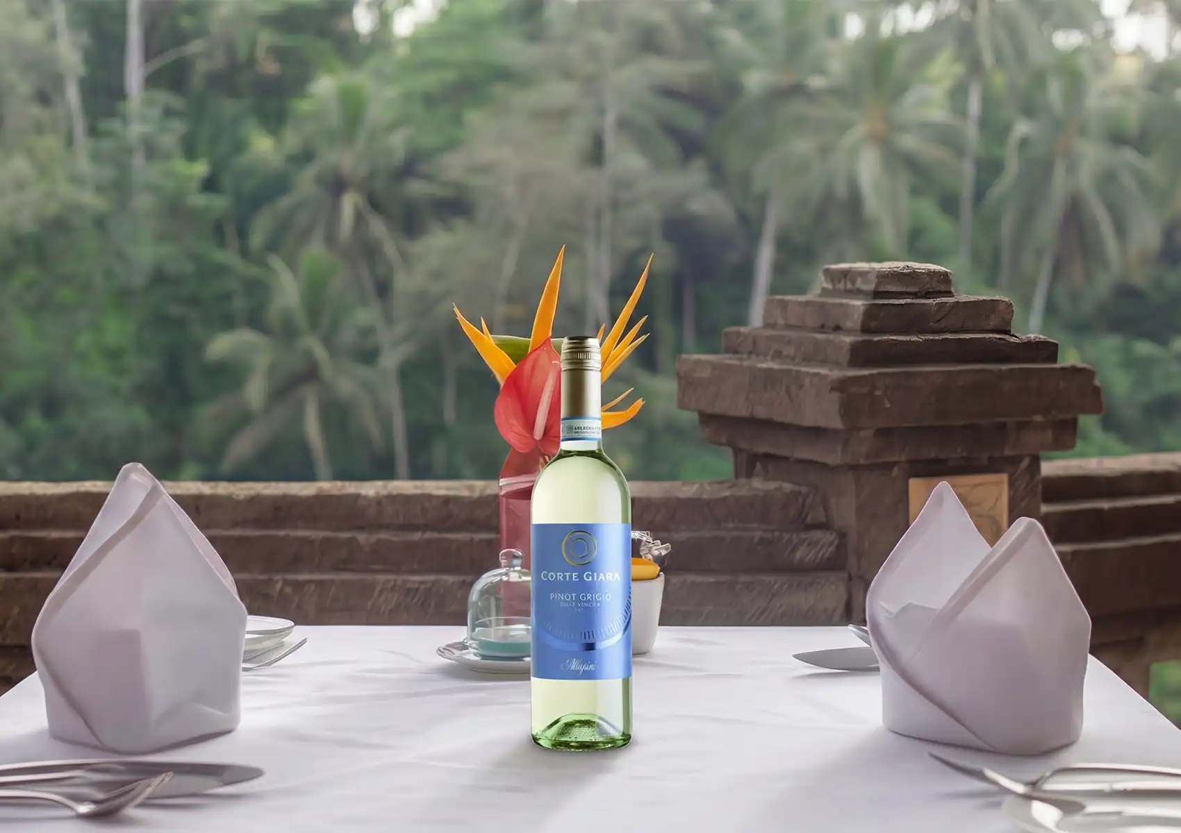 Scenic outdoor restaurant in Ubud with tropical flower centerpiece, wine, and forest view.