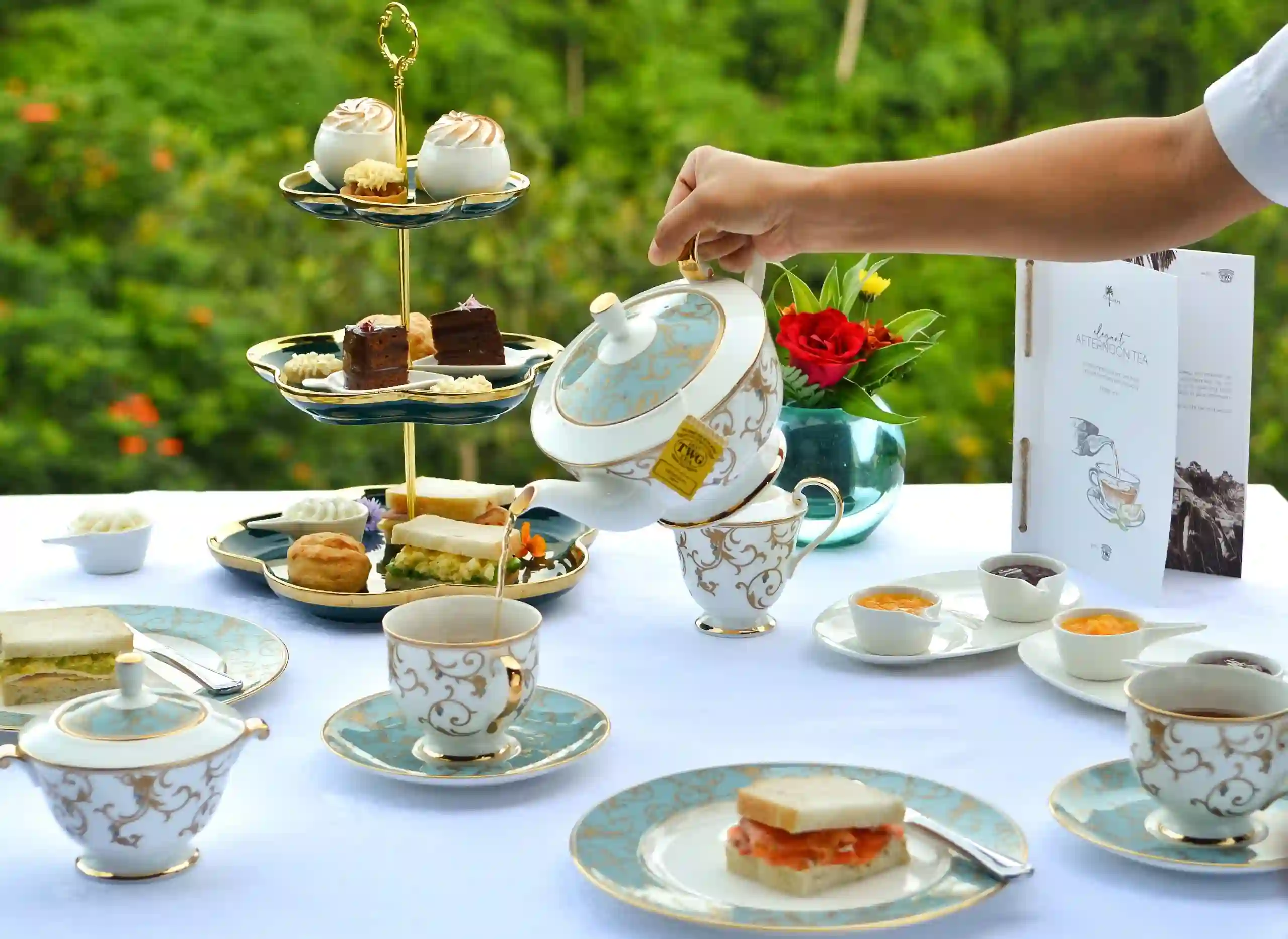 Elegant CasCades Restaurant Afternoon Tea service, featuring a tiered stand of scones, sandwiches, and pastries, alongside fine porcelain teacups and a teapot.