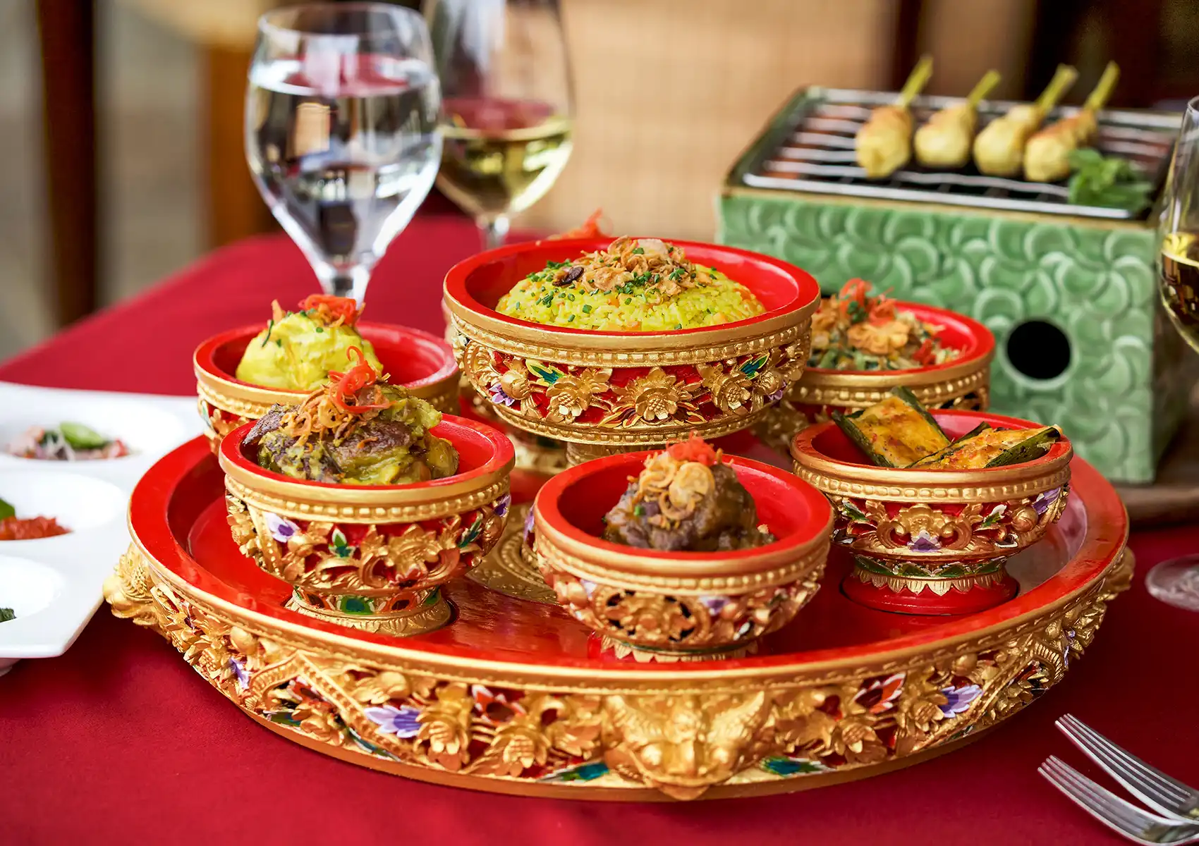 A Balinese Rijsttafel feast featuring yellow rice and various side dishes in decorative red and gold bowls, served at a restaurant in Ubud.
