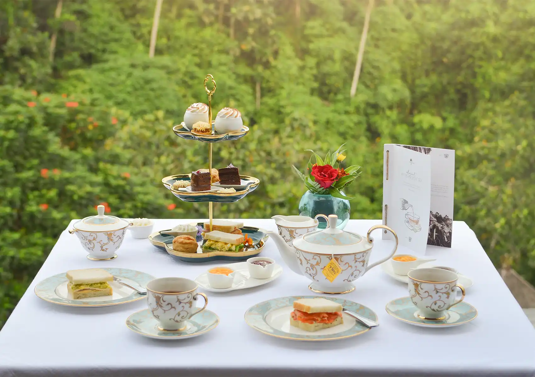 An elegant afternoon tea spread featuring pastries and teacups served on an outdoor terrace at a restaurant in Ubud.
