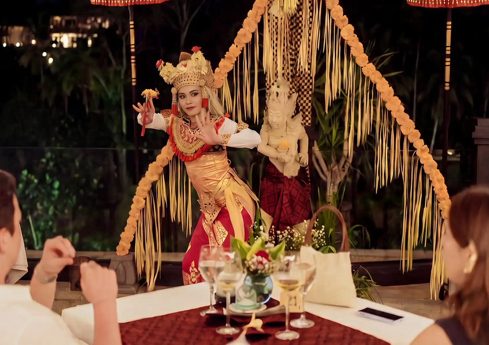 A couple enjoys a traditional Balinese dance performance during an evening dinner at a restaurant in Ubud.